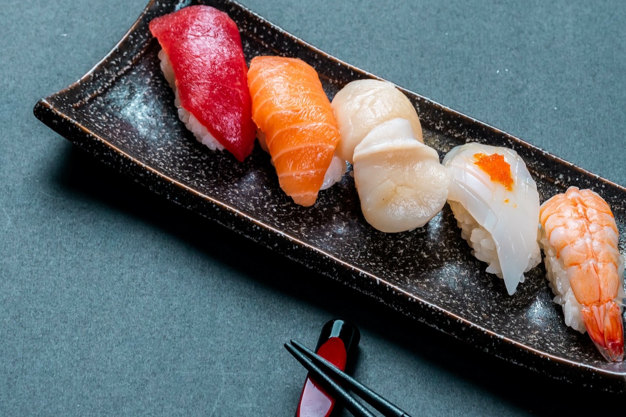 A photo of fresh tuna, salmon, scallop, nigiri, and shrimp sushi and chopsticks
